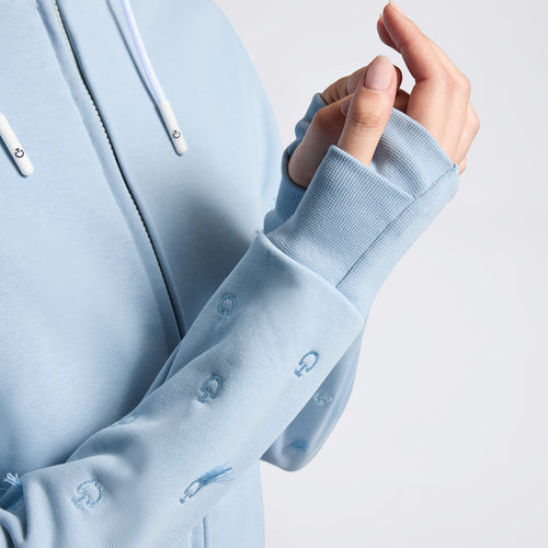 Der Cavalleria Toscana Women's Hoodie ist in einer entspannten Umgebung abgebildet. Der Hoodie liegt locker auf einem Tisch, sodass die Passform und der Schnitt mit dem verstellbaren Reißverschluss und der Kapuze deutlich zur Geltung kommen.